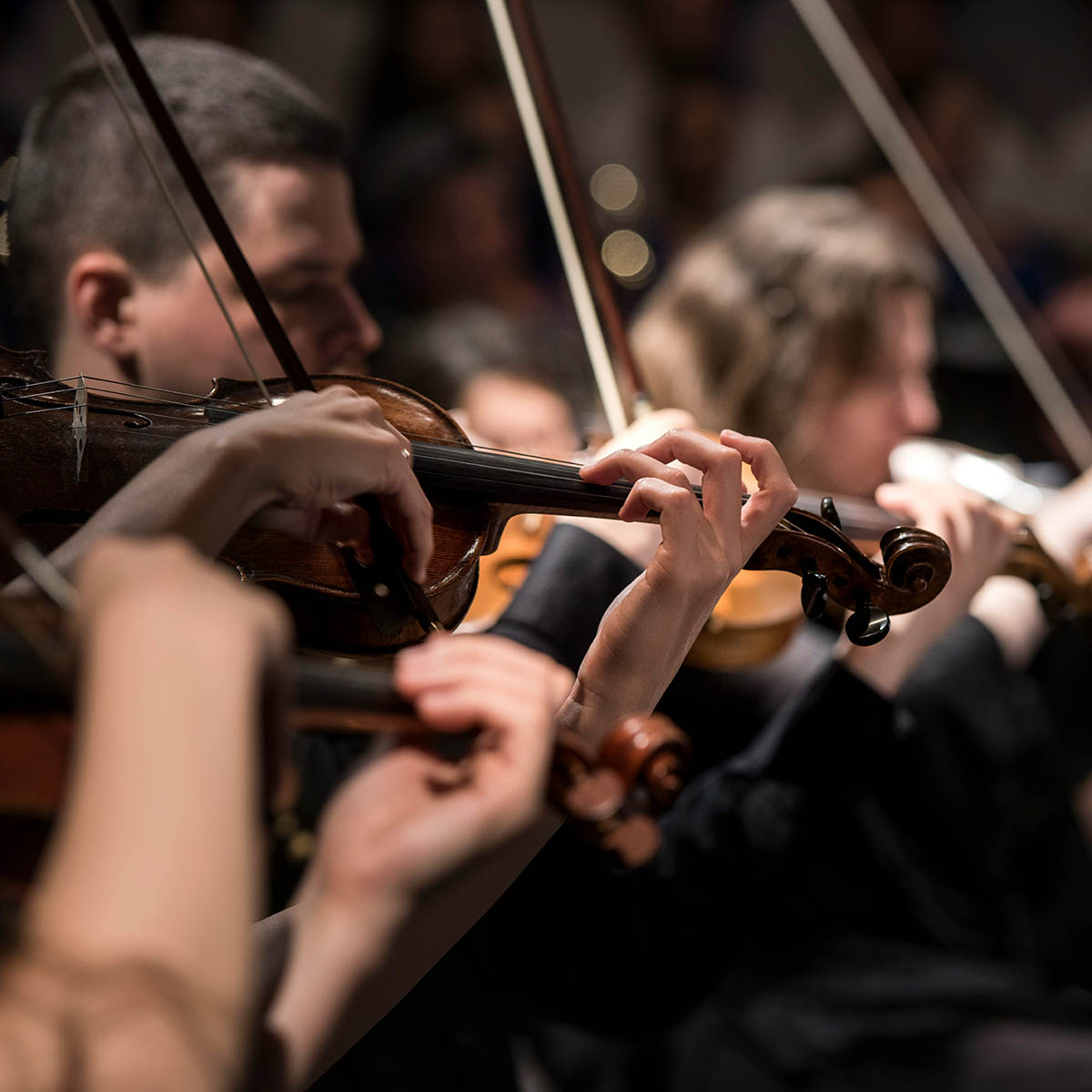 Symphony orchestra performing in dark auditorium.